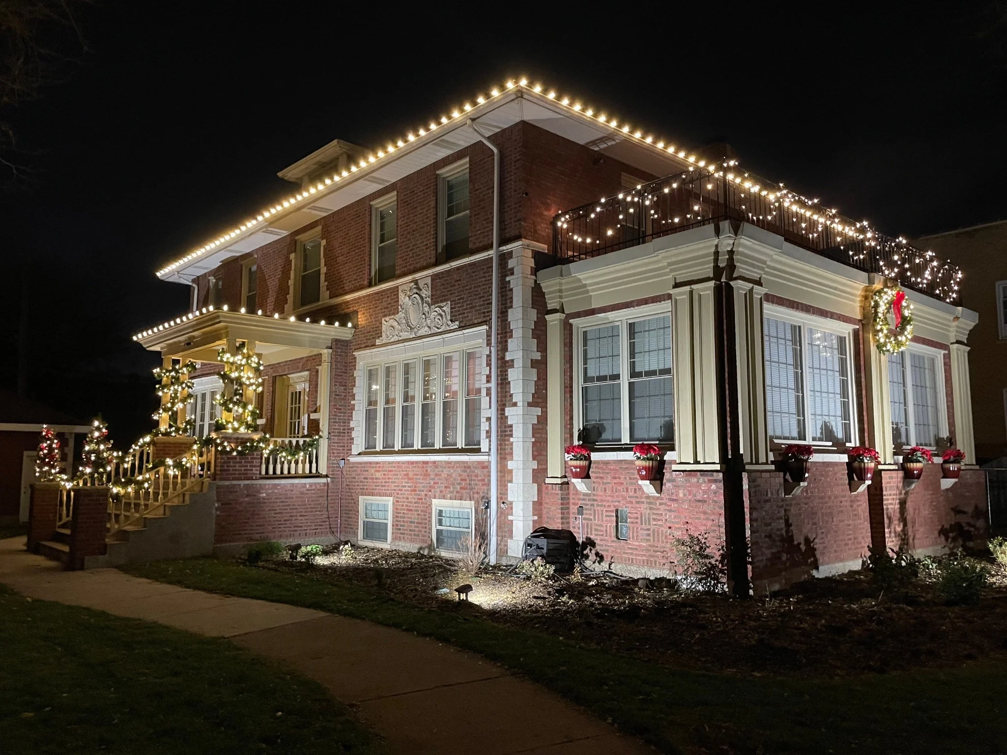 Holiday roofline lighting and decorated brick home